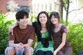 Three brother and sisters sitting outdoors on log, smiling