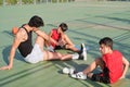 Three brothers doing leg stretching exercises, one of them has a leg prosthesis