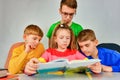 Three brothers and sister study science from a textbook, a girl sits at a book