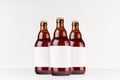 Three brown belgian steinie beer bottles 500ml with blank white label on white wooden board, mock up.