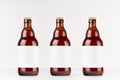 Three brown belgian steinie beer bottles 500ml with blank white label on white wooden board, mock up.