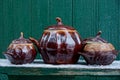 Three brown ceramic pots covered with covers on a table in white snow against a green wall Royalty Free Stock Photo