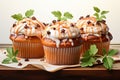 Three brown cupcakes in liners with whipped cream caramel decorations and green leaves standing on a tissue on a white