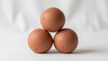 Three brown eggs are arranged in a triangular formation on a smooth white Royalty Free Stock Photo