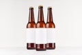 Three brown longneck beer bottles 500ml with blank white label on white wooden board, mock up. Royalty Free Stock Photo