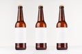 Three brown longneck beer bottles 500ml with blank white label on white wooden board, mock up.