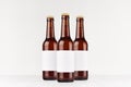 Three brown longneck beer bottles 330ml with blank white label on white wooden board, mock up. Royalty Free Stock Photo