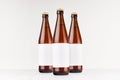 Three brown NRW beer bottles 500ml with blank white label on white wooden board, mock up.
