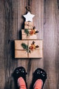 Three brown paper wrapped gifts laid out in the shape of a Christmas tree with star on top. Woman feet in cat slippers Royalty Free Stock Photo