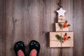 Three brown paper wrapped gifts laid out in the shape of a Christmas tree with star on top. Woman feet in cat slippers Royalty Free Stock Photo