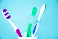 Three brushes for cleaning teeth in a glass white and orange on a blue background. Shaving machines in a glass. Brushes and Royalty Free Stock Photo