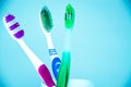 Three brushes for cleaning teeth in a glass white and orange on a blue background. Shaving machines in a glass. Brushes and Royalty Free Stock Photo