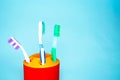 Three brushes for cleaning teeth in a glass white and orange on a blue background. Shaving machines in a glass. Brushes and Royalty Free Stock Photo