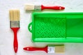 Three brushes with red handles and green paint tray on white concrete background. tools and accessories for home renovation. Top Royalty Free Stock Photo