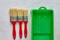 Three brushes with red handles and green paint tray on white concrete background. tools and accessories for home renovation. Top Royalty Free Stock Photo