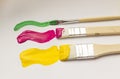 Three brushes with yellow, pink and green paint