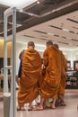 Three Buddhist monks consult each other inside a modern shopping mall in Bangkok, Thailand