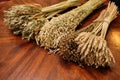 Three bunches of wheat, oats, and flax are arranged on a wooden table