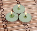 Three burning candles on bamboo mat Royalty Free Stock Photo