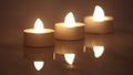 Three burning e-candles in a line with reflection in dark background