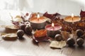Three burning candles, colorful autumn leaves and acorns of northern red oak and amber necklace Royalty Free Stock Photo