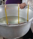 Three burning candles on the edge of the silver font before the Orthodox rite of baptism of a child