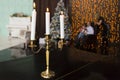 Three burning candles in golden candle holder on black table in the background of silhouettes of family - parents and child