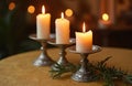 Three burning candles stand on silver candlesticks on table. Candlelight creates romantic luxurious atmosphere. Evergreen tree Royalty Free Stock Photo