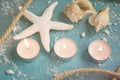 Three burning candles, starfish and shells on the turquoise back Royalty Free Stock Photo