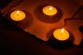 Three burning circle candles and ancient burnt paper sheets Royalty Free Stock Photo