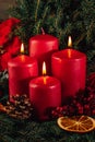 Three burning Red advent candles in advent wreath decoration on wooden dark background. Royalty Free Stock Photo