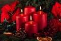 Three burning Red advent candles in advent wreath decoration on wooden dark background. Royalty Free Stock Photo