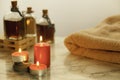 Three burning red candles , bath oils and towel on marble table and grey background Royalty Free Stock Photo