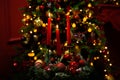 Three burning red candles in the dark against the bokeh of a Christmas tree, lights and decorations Royalty Free Stock Photo