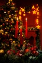 Three burning red candles in the dark against the bokeh of a Christmas tree, lights and decorations Royalty Free Stock Photo