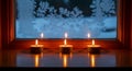 Three Burning Tea Light Candles on Windowsill with Snowy Window Background Royalty Free Stock Photo