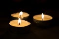 Three burning tea lights on black background Royalty Free Stock Photo