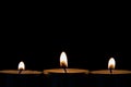 Three burning tea lights on a black background Royalty Free Stock Photo