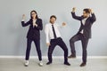 Three business people dancing and celebrate success in business isolated on grey background. Royalty Free Stock Photo