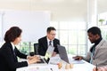 Three business people discussing while sitting at meeting table in office together, multi-ethnic colleagues team working at the Royalty Free Stock Photo