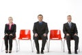 Three Business People Sitting On Red Plastic Seats Royalty Free Stock Photo