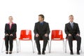 Three Business People Sitting On Red Plastic Seats Royalty Free Stock Photo