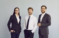 Three business people standing confidently and looking at camera isolated on grey background. Royalty Free Stock Photo