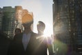 Three business people walking down a city street with sunlight at their back, lens flare Royalty Free Stock Photo