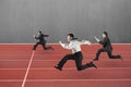 Three businessmen running on red track