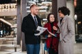 Three businesspeople engaged in a serious business discussion at night with city lights and a festive atmosphere in the Royalty Free Stock Photo