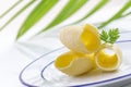 Three Butter curl or roll, on plate front view.greenery in the background Royalty Free Stock Photo