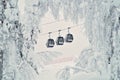 Three cable cars or gondola lifts going up the slope, pictured through the snow-covered trees. Beautiful snowy winter landscape in