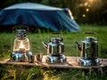 Three camping lanterns on a wooden table in front of a tent