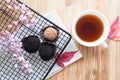 Three candies on a black metal lattice, red leaves, a cup of tea and flowers on a wooden table. Life style.
